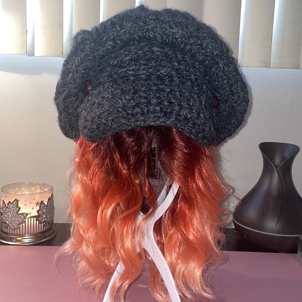 Knitted oversized grey wool cap w/ brown leather buttons on each side of brim.
